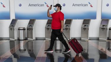 Un pasajero pasa frente a una sección de chequeo de boletos de American Airlines.