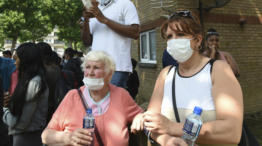 Varias personas se protegen el rostro con mascarillas mientras los bomberos trabajan en las labores de extinción.&nbsp;