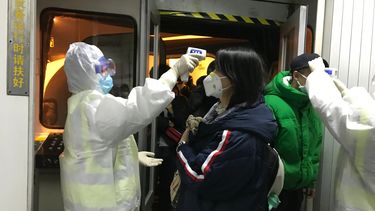 Funcionarios de salud revisan la temperatura corporal de los pasajeros que llegan de la ciudad de Wuhan al aeropuerto de Beijing, el miércoles 22 de enero de 2020.