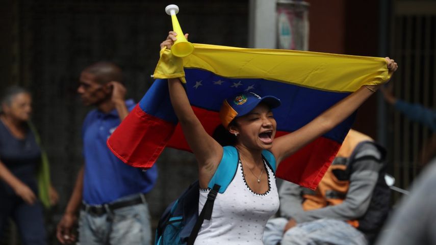 Una mujer lleva la bandera de Venezuela mientras se dirige al punto de concentración de la marcha opositora en contra del régimen de Nicolás Maduro, en Caracas.
