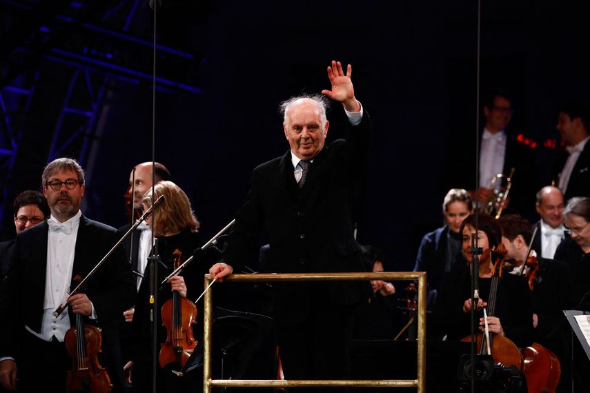 En esta foto de archivo tomada el 9 de noviembre de 2019, el director general de música de la Ópera Estatal de Berlín, Daniel Barenboim, saluda a la multitud con la orquesta Staatskapelle después de actuar durante el espectáculo público por el 30 aniversario de la caída del Muro de Berlín, en la Puerta de Brandenburgo en Berlina.