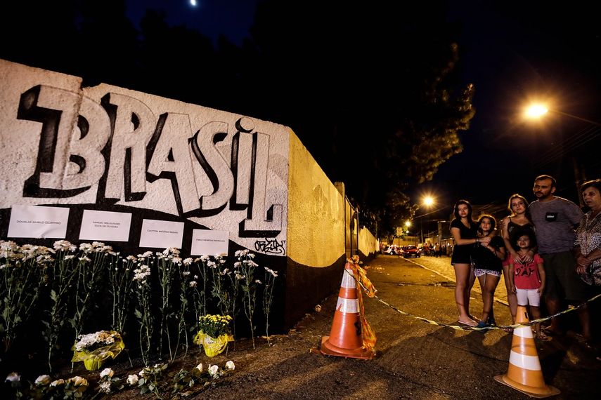 Fotografía de un grafiti con el nombre de la escuela Raúl Brasil en un muro adornado con ramos de flores y los nombres de las víctimas de una masacre este miércoles en Sao Paulo, Brasil.