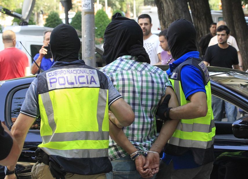 Agentes de la Policía Nacional trasladan a uno de los tres presuntos yihadistas marroquíes detenidos esta madrugada en&nbsp;Madrid, tras el registro realizado en el domicilio de la calle Divino Vallés.