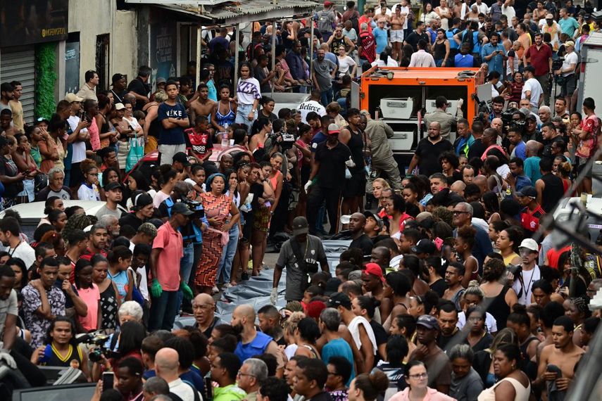 Residentes se encuentran junto a cuerpos alineados frente a un camión morgue en la Plaza Sao Lucas de la favela Vila Cruzeiro en el complejo Penha en Río de Janeiro, Brasil, el 29 de octubre de 2025, tras la Operación Contención.