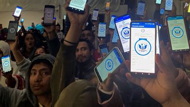 Decenas de migrantes muestran sus teléfonos el domingo 22 de enero de 2023 mostrando en ellos la app CBPOne, en un albergue en Tijuana, México