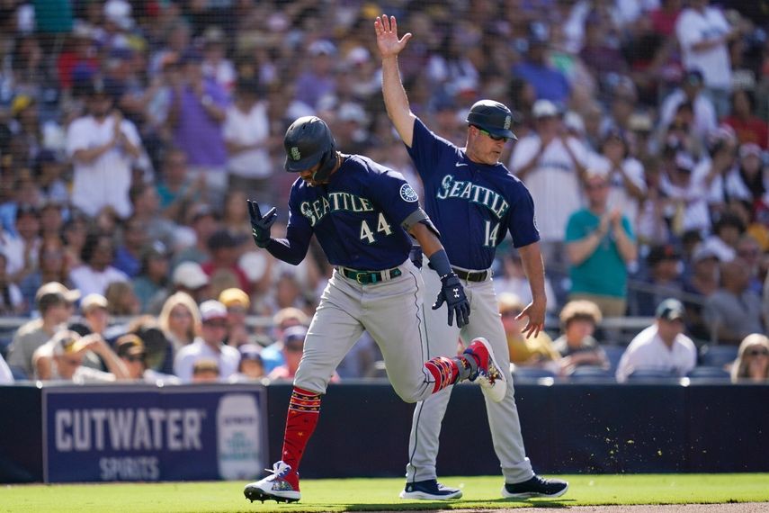 Julio Rodríguez, izquierda, de los Marineros de Seattle, reacciona con el coach de tercera base Manny Acta después de pegar jonrón de dos carreras durante la cuarta entrada del juego de béisbol en contra de los Padres de San Diego, el lunes 4 de julio de 2022.