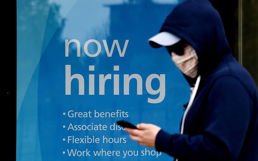 Una persona&nbsp;una&nbsp;m&aacute;scara facial mientras pasa frente un cartel de oferta de empleo en&nbsp;Arlington, Virginia, en mayo de 2020, en medio de la pandemia de COVID-19.
