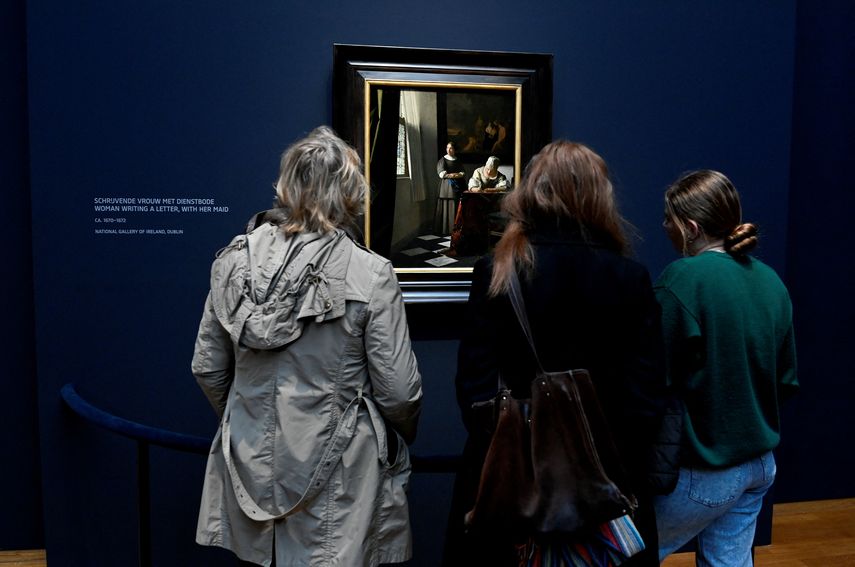 Una mujer toma una foto de una pintura del pintor holandés Johannes Vermeer titulada Mujeres escribiendo una carta, con su doncella en una exposición que se exhibe en el Rijksmuseum de Ámsterdam el 6 de febrero de 2023.