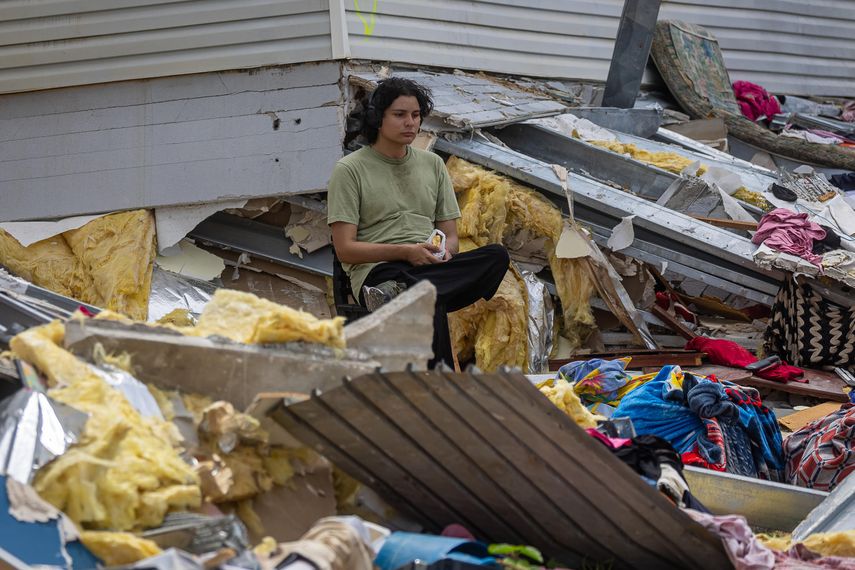 Una persona aguarda en medio de los escombros de edificios colapsados tras los terremotos que asolaron a Venezuela la semana pasada que hacían parte del programa social Misión Vivienda del presidente fallecido Hugo Chávez, este martes en La Guaira (Venezuela).   