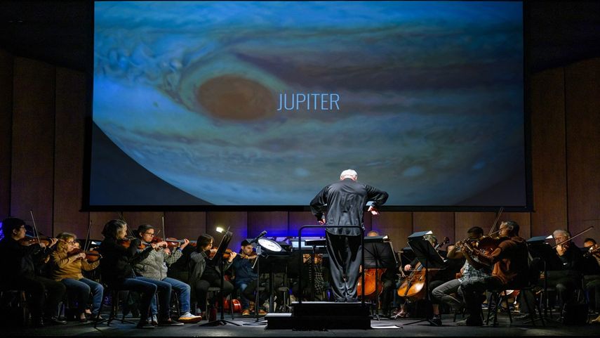Frente a una imagen de la NASA proyectada en una pantalla, el director y director musical de la Filarmónica Nacional, Piotr Gajewski, ensaya Cosmic Cycles, A Space Symphony del compositor Henry Dehlinger, en Capital One Hall en Arlington, Virginia, el 11 de mayo de 2023.