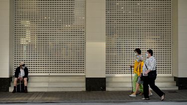 Tres mujeres pasan caminando junto a un hombre, sentado ante la entrada de un establecimiento, todos con mascarilla para frenar la propagaci&oacute;n del coronavirus, en el &uacute;ltimo d&iacute;a de la cuarentena, en Pamplona, el 20 de junio de 2020.&nbsp; &nbsp; &nbsp;