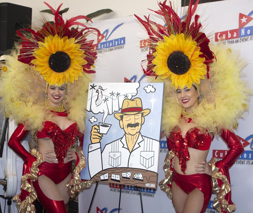 Dos bailarinas posan junto al afiche de Cuba Nostalgia, creado por el artista cubanoamericano Carlos A. Navarro.