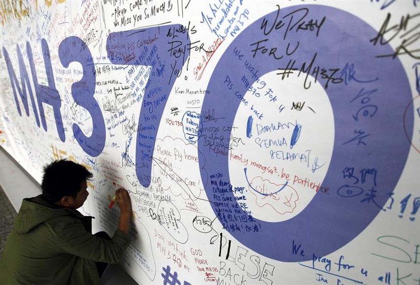 Fotografía de archivo del 13 de marzo de 2014 de un hombre escribiendo mensajes en honor a las víctimas del vuelo MH370 de Malaysia Airlines. (EFE)