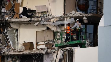 Trabajadores de rescate en una grúa inspeccionan los restos de un edificio parcialmente derrumbado en Surfside al norte de Miami Beach, Florida.