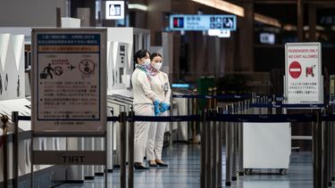 Los miembros del personal se paran en la puerta de salida del aeropuerto internacional Haneda de Tokio el 29 de noviembre de 2021, cuando Japón anunció planes para prohibir a todos los nuevos viajeros extranjeros sobre la variante Omicron de COVID-19. &nbsp;
