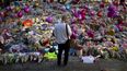 Un hombre observa flores y globos colocados en honor de las víctimas de un ataque con bomba en un concierto de Ariana Grande, el 26 de mayo de 2017, en la Plaza St. Ann, en el centro de Manchester, Inglaterra.