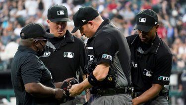 Foto del 22 de julio del 2022, Kelvin Pickens de MLB Network inspecciona el radio y la diadema de repeticiones con los umpires Corey Blaser, Edwin Moscos y Dan Bellino en un juego en Chicago. 