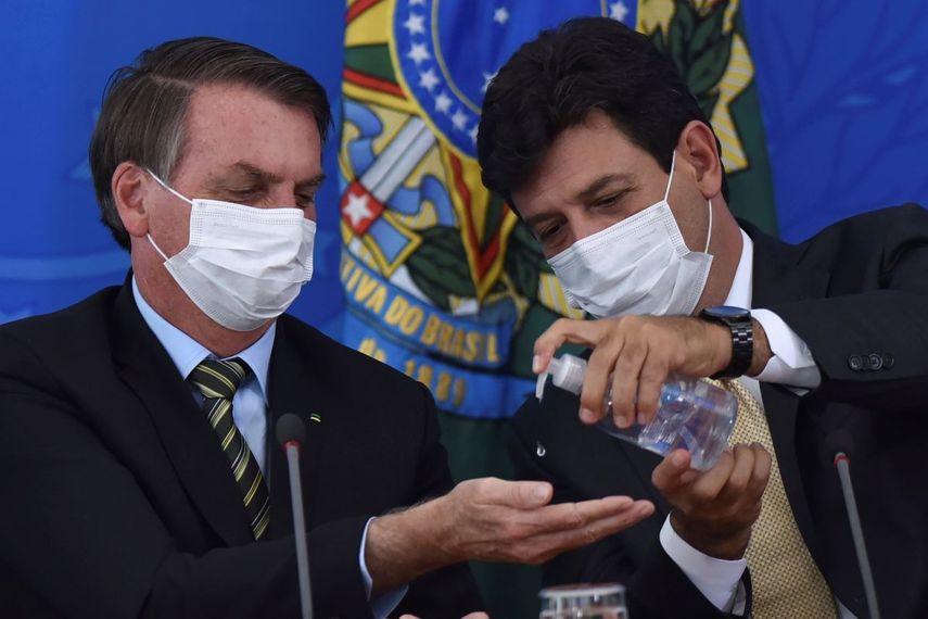 &nbsp; El ahora exministro de salud de Brasil Luiz Henrique Mandetta, derecha, aplica desinfectante en las manos al presidente Jair Bolsonaro durante una conferencia de prensa en el Palacio Presidencial de Planalto en Brasilia, el 18 de marzo del 2020.