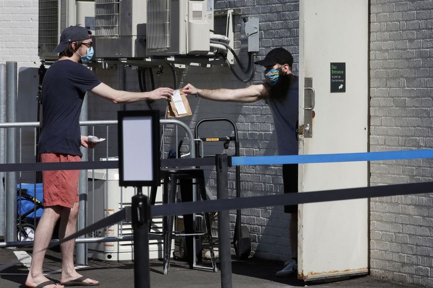 Foto tomada el 26 de mayo del 2020 del empleado de una tienda de marihuana entregándole un paquete a un cliente en Brookline, Massachusetts. 
