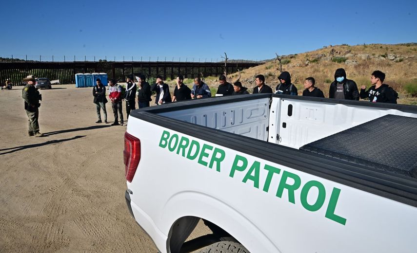 Agentes de la Patrulla de Protección Fronteriza detienen a inmigrantes que cruzaron hacia territorio estadounidense.