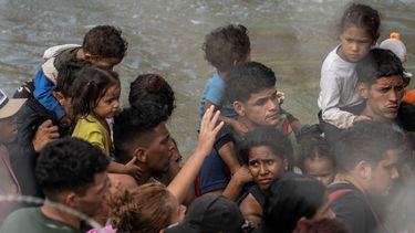 Migrantes cargan niños pequeños esperan en un barco de la Patrulla Fronteriza de Estados Unidos que los llevará a un área de procesamiento, luego de horas de espera bajo el sol a lo largo del Río Grande, en Eagle Pass, Texas, el 25 de septiembre de 2023.