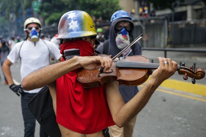 Un manifestante toca violín en una de las marchas opositoras venezolanas que pretendían llegar al centro de Caracas este lunes 8 de mayo de 2017.&nbsp;