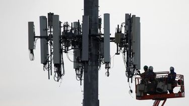 Empleados trabajan en una torre de comunicaciones de la compañía Verizon.