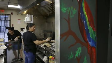La salvadoreña Anna López (zq) y la hondureña María Erazo trabajando en la cocina de un restaurante de Chelsea, Massachusetts.