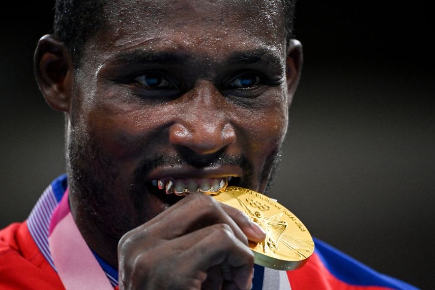 Julio La Cruz, medallista de oro de Cuba, muerde su medalla en el podio después de la pelea final de boxeo masculino pesado (81-91 kg) durante los Juegos Olímpicos de Tokio 2020