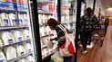 Una mujer toma un galón con leche en un supermercado.