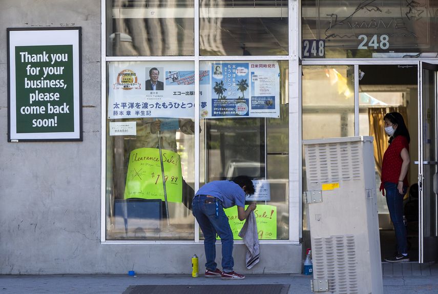 Una pareja limpia el escaparate de su tienda en el barrio Little Tokyo de Los &Aacute;ngeles.