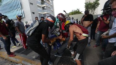 Manifestantes opositores ayudan a un hombre herido este miércoles en las calles de Caracas (Venezuela).