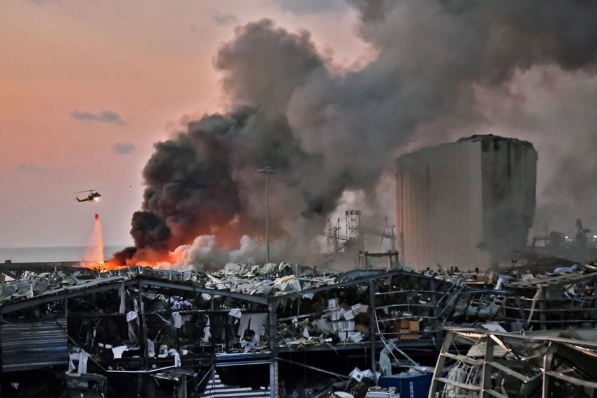 Un helic&oacute;ptero lanza agua en la zona de desastre para apagar las enormes llamas, en el puerto de Beirut, en el Libano.