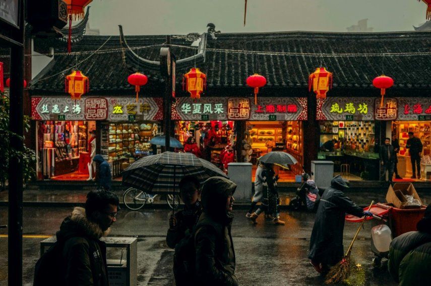 Ciudadanos chinos se protegen de la lluvia en una calle comercial en Pekín, China.