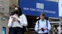 Dos personas caminan frente a un letrero que anuncia a Wall Street. Dos personas caminan frente a un letrero que anuncia a Wall Street.
