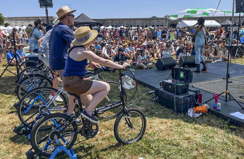 La artista Madi Diaz (derecha) se presenta en el Festival Folk de Newport en un escenario alimentado con electricidad generada por los asistentes en bicicletas fijas (a la izquierda) el viernes 22 de julio de 2022, en Newport, Rhode Island.