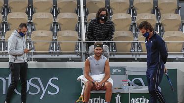 El espa&ntilde;ol Rafael Nadal, centro, su entrenador Francisco Roig, derecha, y parte de su equipo con cubrebocas se re&uacute;ne durante una pausa en una pr&aacute;ctica en el estadio Roland Garros en Par&iacute;s, el viernes 25 de septiembre de 2020
