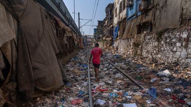 Un hombre camina en una vía ferroviaria repleta de plásticos y otros desechos en el Día de la Tierra, en Mumbai, India, el 22 de abril de 2024.