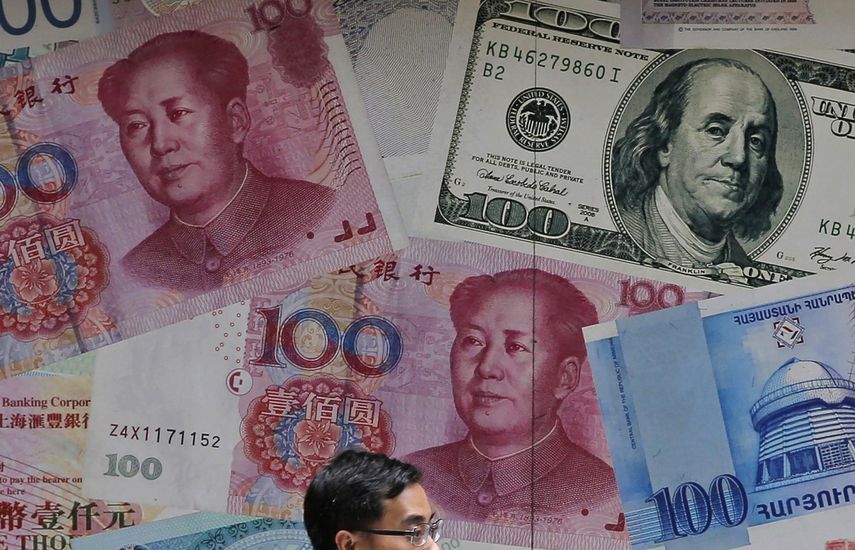 En esta fotografía de archivo del 10 de junio de 2019, un hombre camina junto a una casa de cambio decorada con diferentes billetes en Central, un distrito de negocios en Hong Kong.&nbsp;