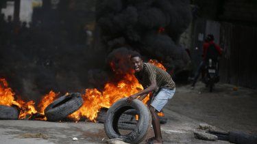 Un manifestante coloca neumáticos en una barricada en llamas durante una protesta para exigir la renuncia del primer ministro, Ariel Henry, en Puerto Príncipe, Haití, el 7 de febrero de 2024.&nbsp;