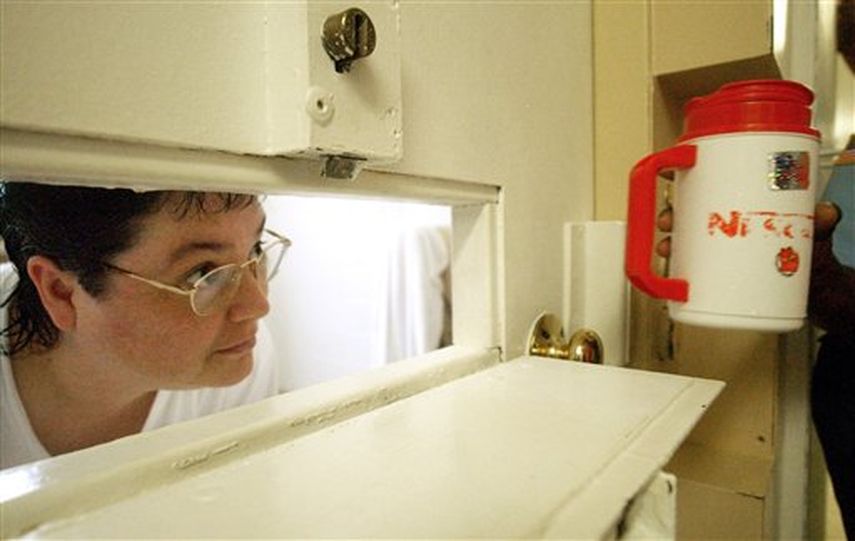 Kelly Gissendaner, la única mujer que aguarda ser ejecutada en Georgia, se asoma a través de su celda para recibir un recipiente con hielo, en la prisión Metro State en Atlanta. Gissendaner iba a ser ejecutada el lunes 2 de marzo de 2015. AP 