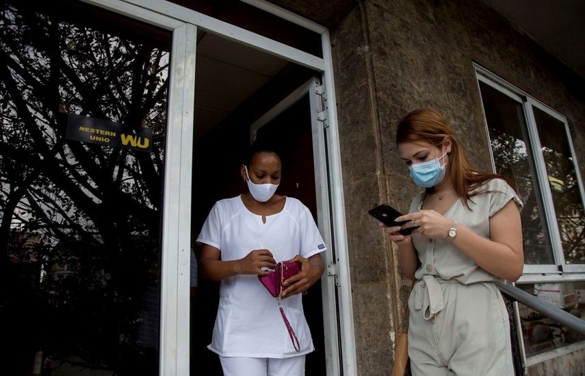 Una trabajadora de salud cubana deja una oficina de Western Union después de cobrar dinero mientras otra clienta espera su turno el último día de trabajo de la oficina en La Habana, Cuba.&nbsp;