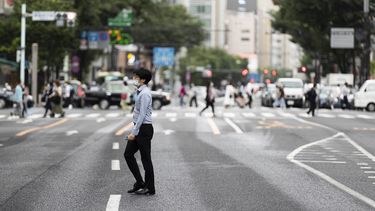 Un hombre con mascarilla cruza una calle en el popular barrio comercial de Ginza, en Tokio, el 21 de mayo de 2021.&nbsp;