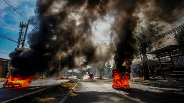 Un hombre sostiene una bandera chilena en medio de barricadas en llamas durante una protesta en demanda de ayuda económica del gobierno y la aprobación del tercer retiro anticipado de fondos de pensiones en medio de la crisis desencadenada por la pandemia de COVID-19 en la comuna pobre de Pintana, en Santiago el 22 de abril de 2021.&nbsp;