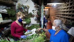 En esta foto del 20 de marzo de 2020, una mujer, con una mascarilla protectora, compra hierbas frescas en un mercado en Caracas, Venezuela. Ante la llegada de los primeros casos de coronavirus COVID-19 algunos venezolanos recurren a plantas como el toronjil, el hinojo y el limoncillo, y frutos como el lim&oacute;n, alegando que eso los ayuda a mejorar el sistema inmunol&oacute;gico y protegerse de la pandemia. M&eacute;dicos y organizaciones cient&iacute;ficas sostienen que el consumo de bebedizos de hierbas no sirve para prevenir ni tratar la enfermedad.&nbsp;