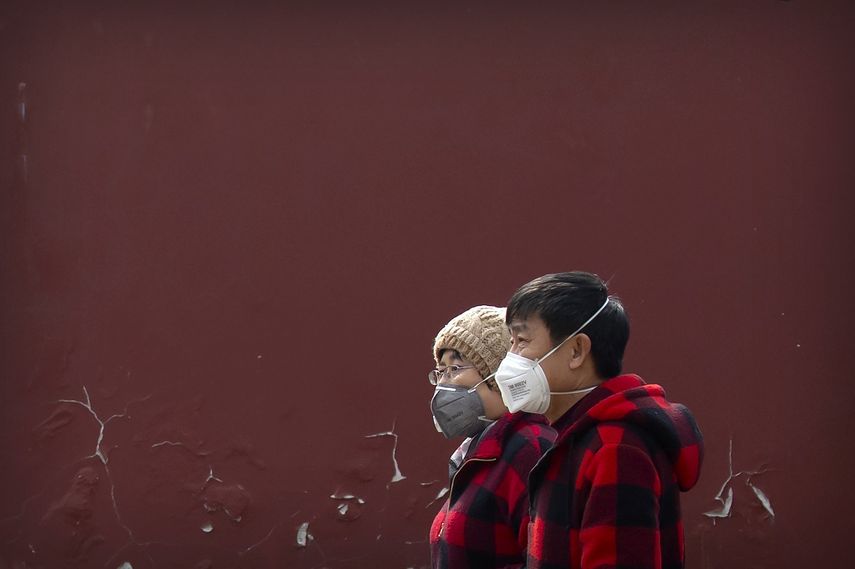 Dos personas con mascarillas sobre la boca caminan en Beijing, el 21 de febrero de 2020.&nbsp;