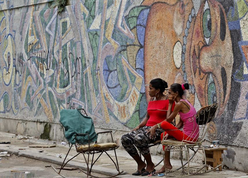 Dos mujeres sentadas frente a una pared decorada con graffitis en La Habana, Cuba, en agosto de 2018.