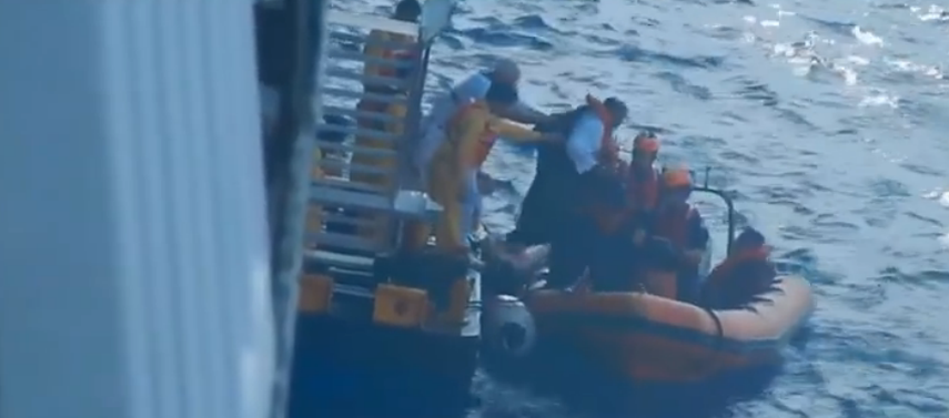 Los balseros siendo remolcados por un bote enviado por el crucero Disney Magic