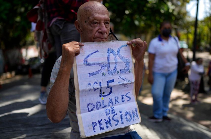 Carlos Blanco, de 84 años, supervisor de ambulancias retirado, sostiene un cartel que anuncia el pago mensual de su pensión de $1.50 dólares durante una protesta en que demandaban un incremento en los pagos en medio de una inflación récord en Caracas, Venezuela. 