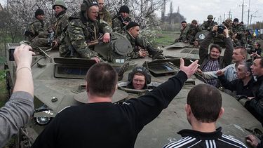 Unas personas bloquean el paso de vehículos del ejército ucraniano que se dirigen al poblado de Kramatorsk, Ucrania, el miércoles 16 de abril de 2014.